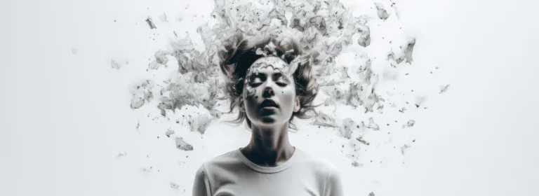 Uma mulher de camisa branca está de pé contra um fundo claro, com os olhos fechados, e o cabelo e as partículas ao redor lembram uma explosão, transmitindo uma sensação de caos e introspecção.