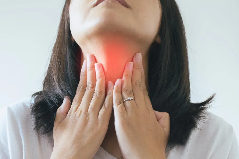 Uma mulher de camisa branca segura a garganta, destacada em vermelho, indicando dor ou desconforto.