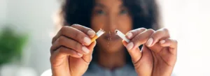 Uma pessoa parte um cigarro ao meio, espalhando pedaços de tabaco.